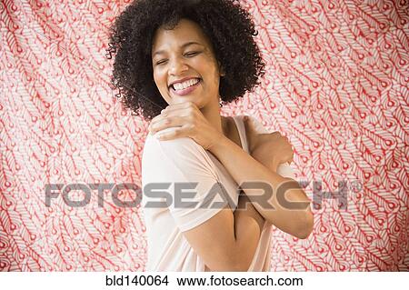 Picture - Smiling woman hugging herself. Fotosearch