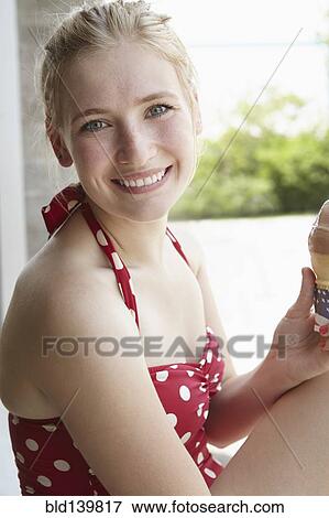Stock Photo - Smiling woman in swimsuit eating ice cream cone. Fotosearch