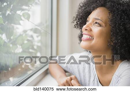Stock Photography - Smiling woman looking out window. Fotosearch