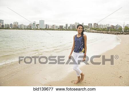Smiling woman walking on urban beach View Large Photo Image Stock Photo - Smiling woman walking on urban beach. Fotosearch