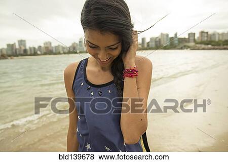 Stock Photo - Smiling woman walking on urban beach. Fotosearch