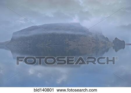 Snowy mountain under cloudy sky reflected in lake View Large Photo Image Stock Image - Snowy mountain under cloudy sky reflected in lake. Fotosearch