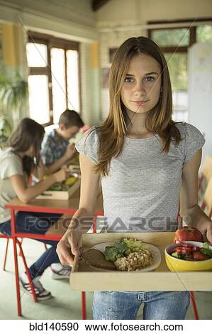 Stock Image - Student carrying lunch tray in school cafeteria. Fotosearch