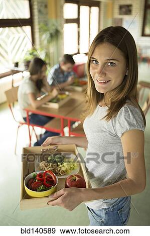 Stock Photo - Student carrying lunch tray in school cafeteria. Fotosearch