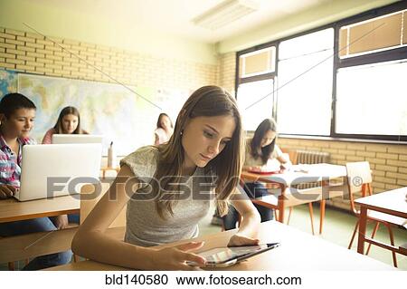 Stock Image - Student using digital tablet in classroom. Fotosearch