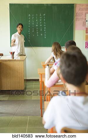 Stock Image - Students and teacher in classroom. Fotosearch