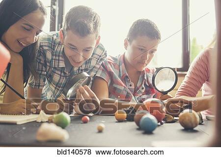 Stock Photo - Students examining models of planets in classroom. Fotosearch