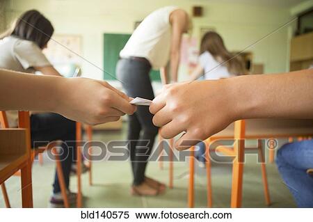 Stock Photography - Students passing notes in classroom. Fotosearch
