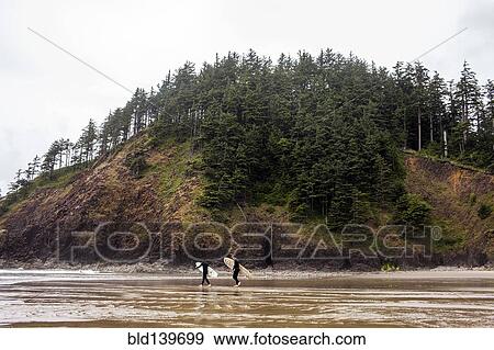 Stock Photo - Surfers carrying surfboards on beach. Fotosearch
