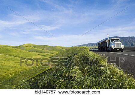 Stock Photo - Truck driving on remote road in rolling landscape. Fotosearch