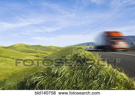 Stock Photo - Truck driving on remote road in rolling landscape. Fotosearch