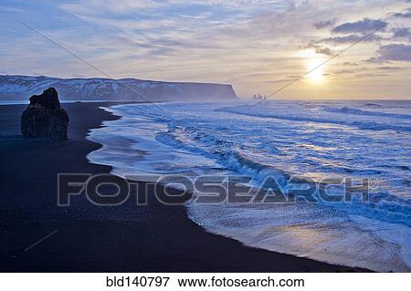 Waves washing up by rock formation on beach View Large Photo Image Stock Photo - Waves washing up by rock formation on beach. Fotosearch