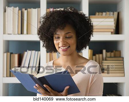 Stock Photo - Woman reading book in library. Fotosearch