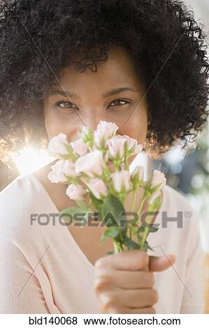 Stock Photo - Woman smelling bouquet of roses indoors. Fotosearch