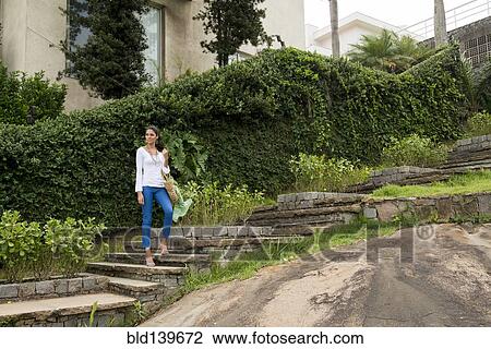 Stock Image - Woman standing on stone steps. Fotosearch