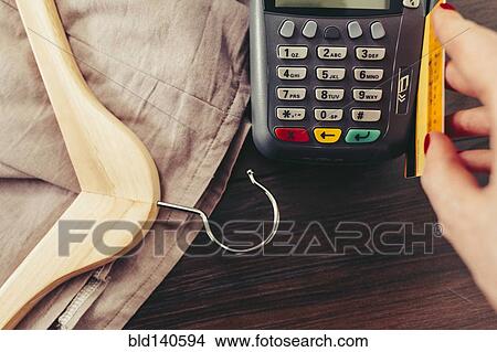 Picture - Woman swiping credit card through credit card reader. Fotosearch