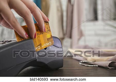 Stock Image - Woman swiping credit card through credit card reader. Fotosearch