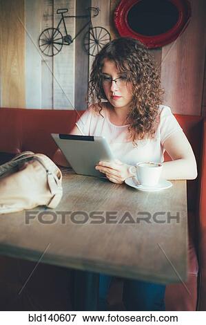 Stock Photo - Woman using digital tablet in cafe. Fotosearch