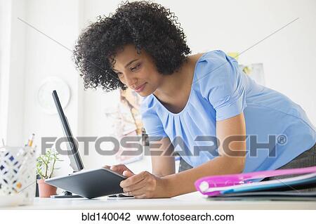 Woman using digital tablet on desk View Large Photo Image Stock Image - Woman using digital tablet on desk. Fotosearch