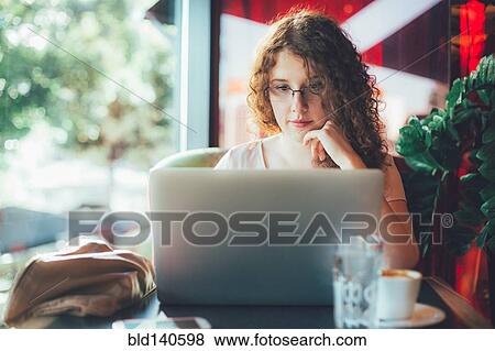 Stock Photo - Woman using laptop computer in cafe. Fotosearch