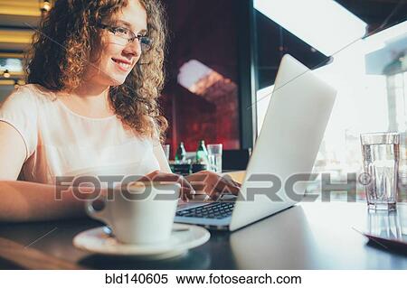 Stock Photography - Woman using laptop computer in cafe. Fotosearch