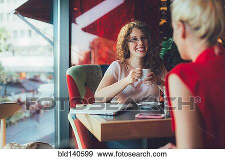 Stock Photo - Women drinking coffee together in cafe. Fotosearch
