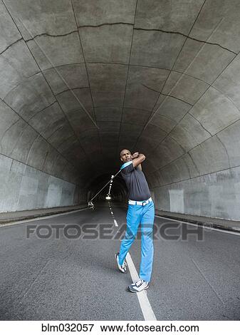 Stock Photo - Black man playing golf in urban tunnel. Fotosearch