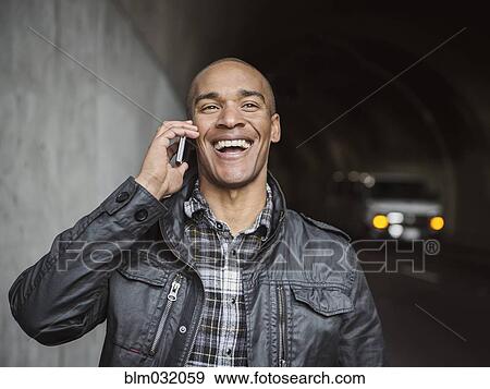 Stock Photo - Black man talking on cell phone in urban tunnel. Fotosearch