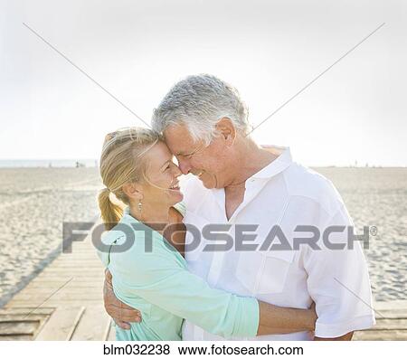 Stock Photo - Caucasian couple hugging on beach. Fotosearch
