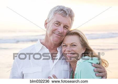 Stock Photograph - Caucasian couple hugging on beach. Fotosearch