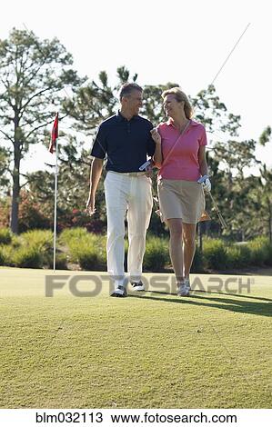 Stock Image - Caucasian couple playing golf on course. Fotosearch