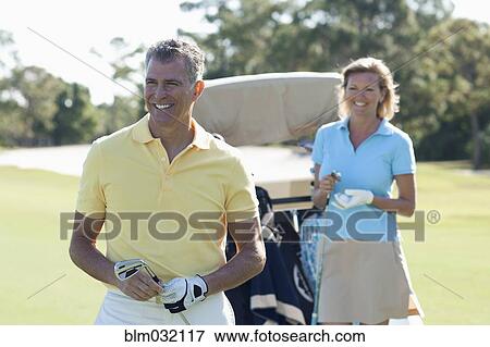 Stock Photo - Caucasian couple playing golf on course. Fotosearch