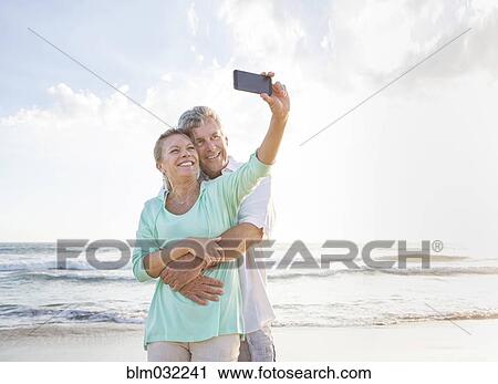 Caucasian couple taking cell phone selfie on beach View Large Photo Image Stock Image - Caucasian couple taking cell phone selfie on beach. Fotosearch