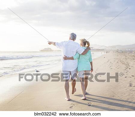Stock Image - Caucasian couple walking on beach. Fotosearch