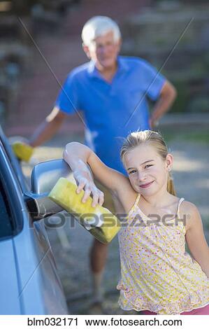 Stock Image - Caucasian grandfather and granddaughter washing car outdoors. Fotosearch