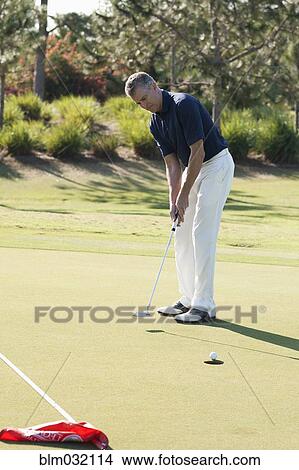 Picture - Caucasian man putting on golf course. Fotosearch
