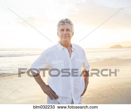 Stock Image - Caucasian man smiling on beach. Fotosearch
