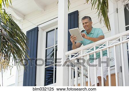 Caucasian man using digital tablet on balcony View Large Photo Image Stock Photography - Caucasian man using digital tablet on balcony. Fotosearch