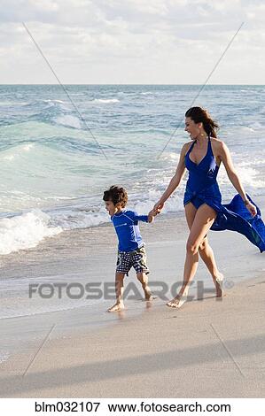 Stock Photo - Caucasian mother and son walking on beach. Fotosearch