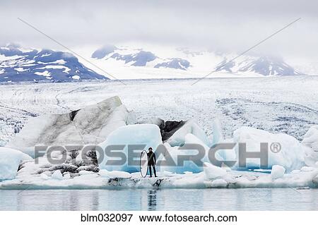 Caucasian surfer carrying board near glacial water View Large Photo Image Stock Photo - Caucasian surfer carrying board near glacial water. Fotosearch