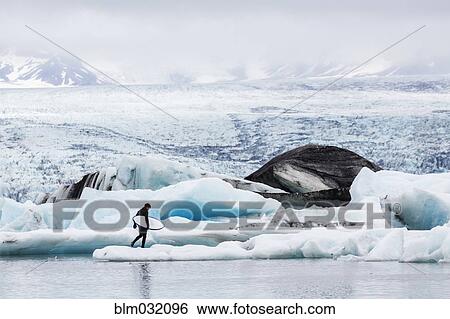 Caucasian surfer carrying board near glacial water View Large Photo Image Stock Photograph - Caucasian surfer carrying board near glacial water. Fotosearch