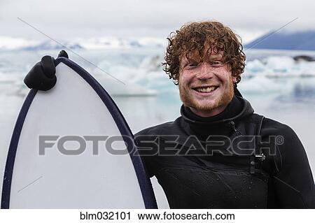 Caucasian surfer holding board near glacial water View Large Photo Image Stock Image - Caucasian surfer holding board near glacial water. Fotosearch