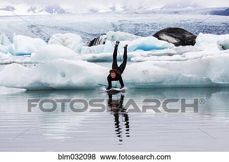 Caucasian surfer leaping on board into glacial water View Large Photo Image Stock Photo - Caucasian surfer leaping on board into glacial water. Fotosearch