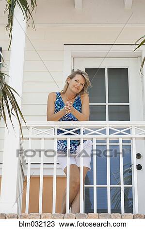 Stock Image - Caucasian woman standing on balcony. Fotosearch