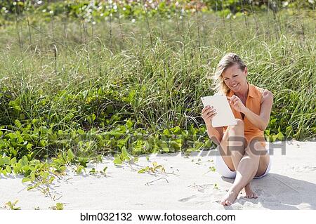Caucasian woman using digital tablet on beach View Large Photo Image Stock Image - Caucasian woman using digital tablet on beach. Fotosearch