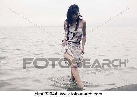 Picture - Caucasian woman wading in water on beach. Fotosearch