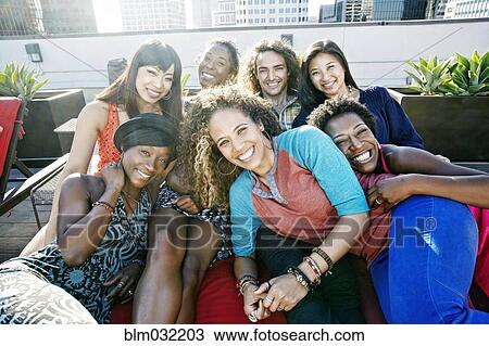 Stock Image - Friends hugging on urban rooftop. Fotosearch