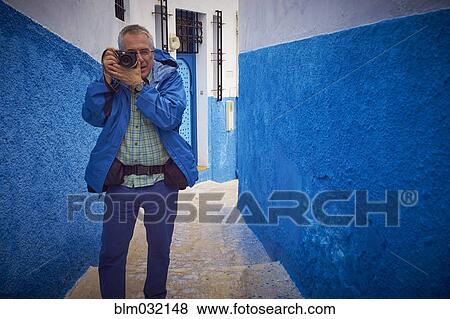 Man photographing in colorful historical street, Chefchaouen, Chefchaouen, Morocco View Large Photo Image Stock Photo - Man photographing in colorful historical street, Chefchaouen, Chefchaouen, Morocco. Fotosearch