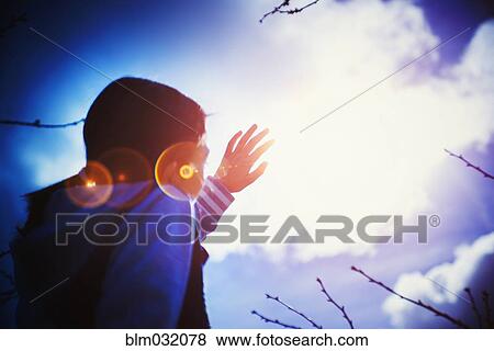 Mixed race girl shielding herself from sun lens flare View Large Photo Image Stock Photo - Mixed race girl shielding herself from sun lens flare. Fotosearch