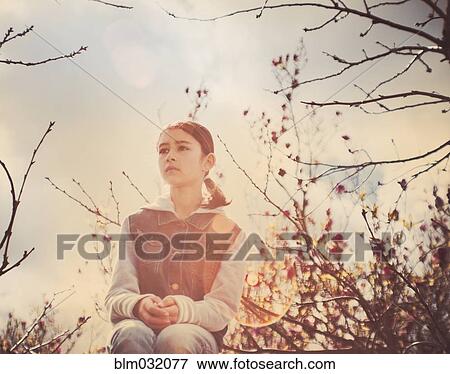 Stock Photo - Mixed race girl sitting in tree outdoors. Fotosearch